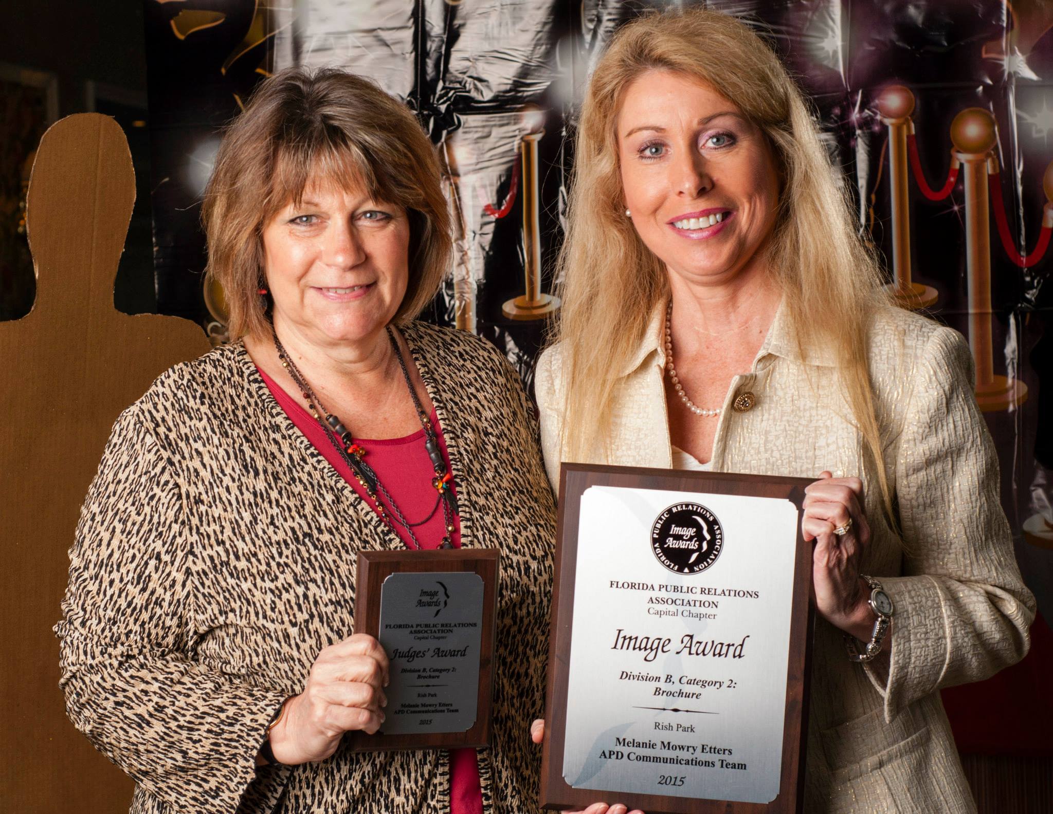 APD Chief of Staff Karen Hagan and Communications Dir. Melanie Etters hold two of APD's four awards.